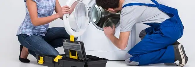 Washer repair technician inspecting a front-load washing machine with tools in Sioux Falls, SD