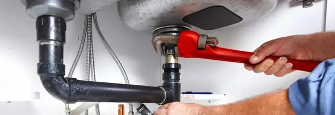 Garbage disposal repair technician tightening the sink drain and disposal connection in Sioux Falls, SD
