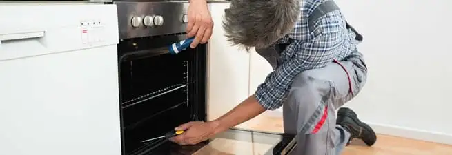 Oven repair technician inspecting and servicing an electric oven in Sioux Falls, SD