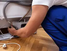 Appliance repair technician fixing refrigerator water line and connections in Sioux Falls, SD