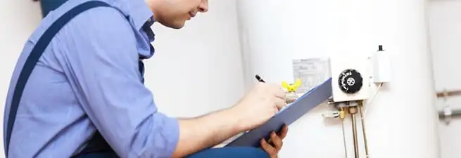 Water heater repair technician inspecting the unit and recording service notes in Sioux Falls, SD