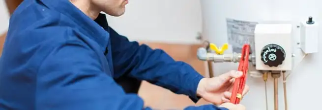 Water heater repair technician adjusting the temperature control and gas valve in Sioux Falls, SD
